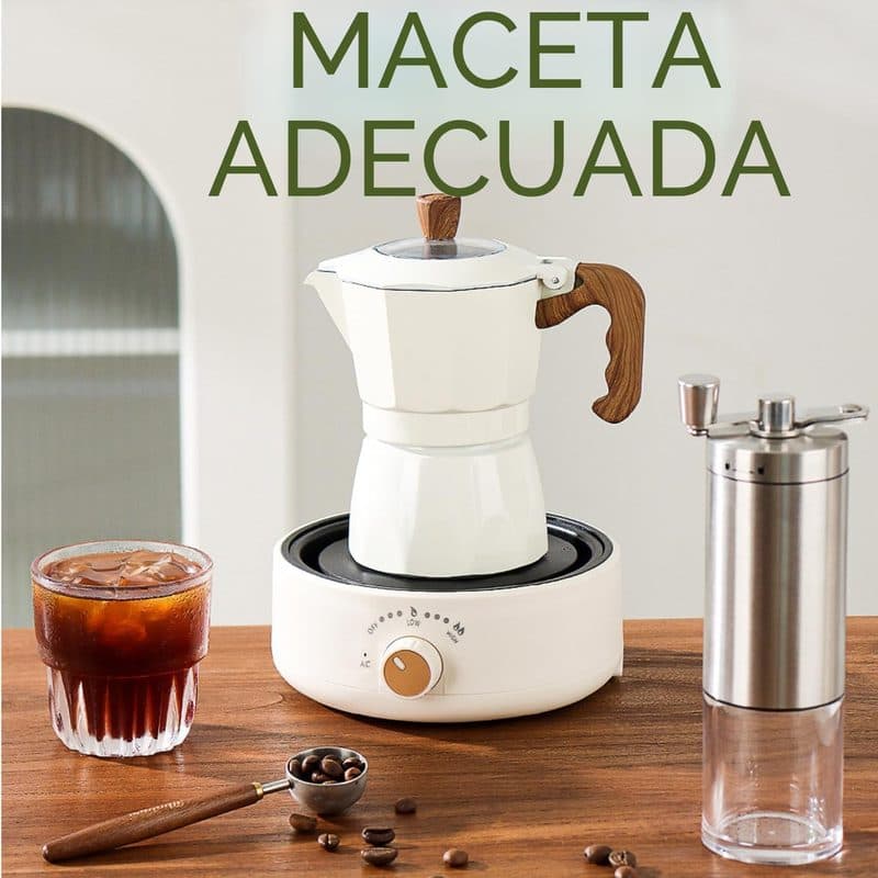 Cafetera moka sobre la placa eléctrica junto a un café helado y granos de café en una mesa de madera